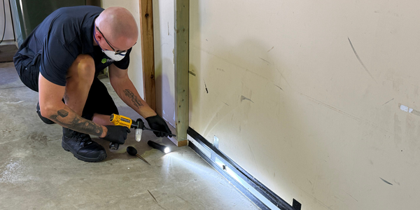 Pest technician applying treatment with a duster along a wall frame