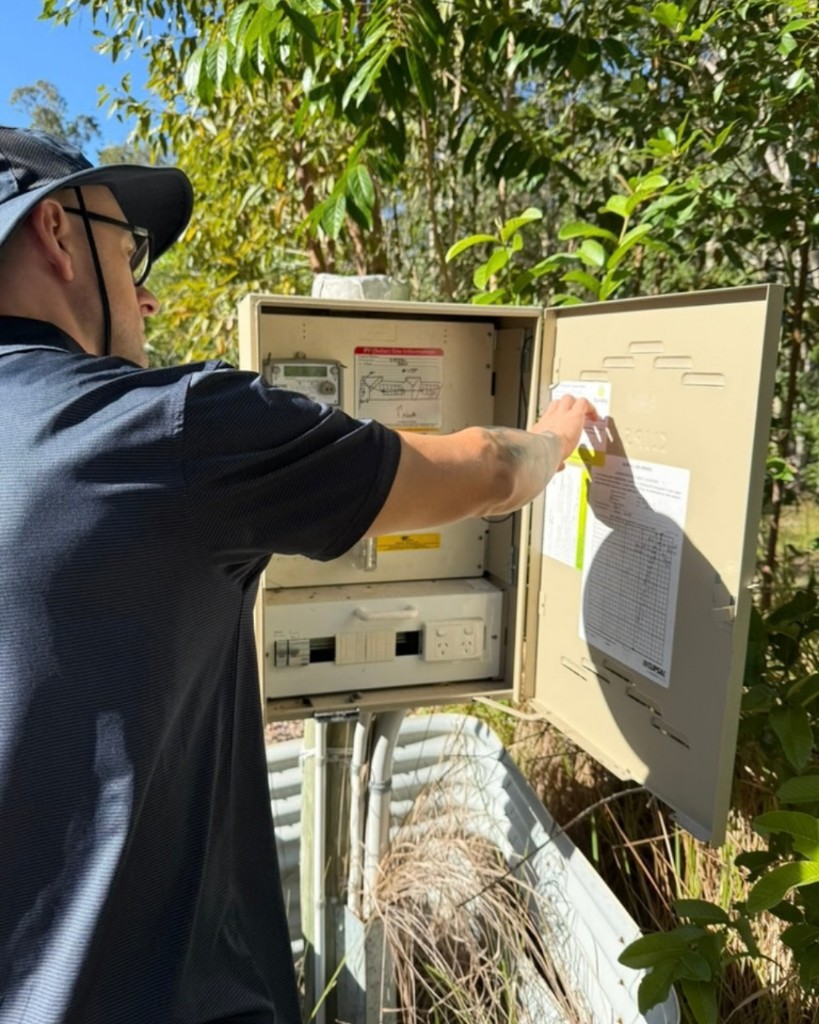 Pest management technician inspecting an outdoor electrical enclosure and treatment records