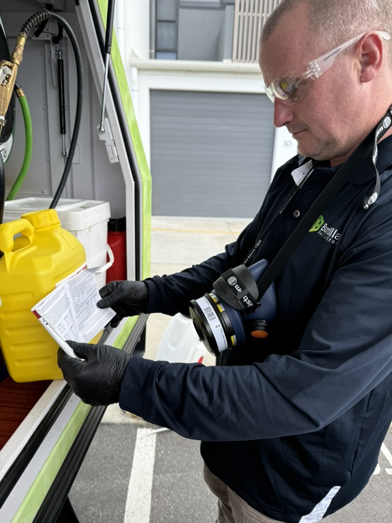 Pest control technician reviewing treatment documentation next to a service vehicle