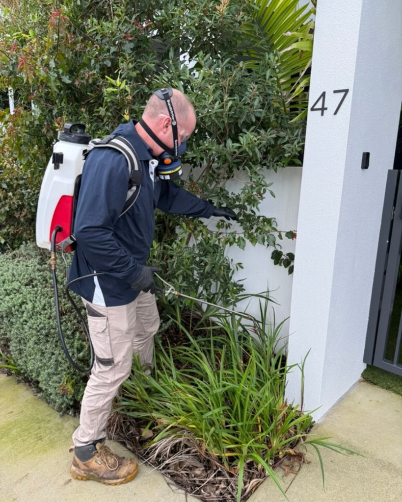 Technician using a backpack sprayer for an outdoor perimeter treatment