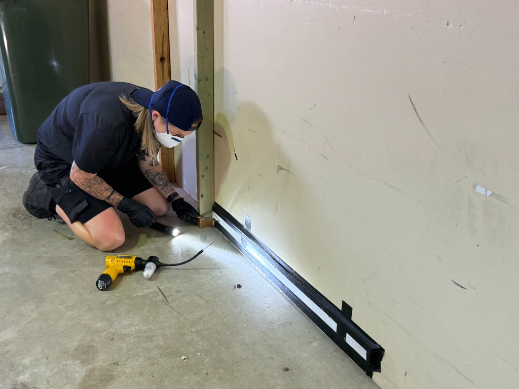 Pest control technician inspecting a wall base during practical workplace training
