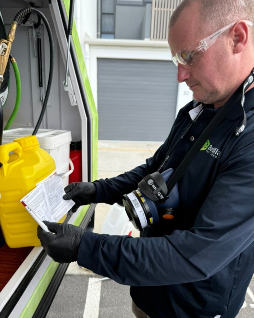 Pest control technician reviewing chemical documentation beside a service vehicle